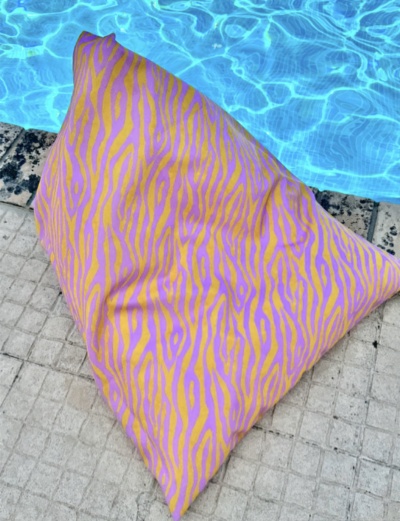 Almofada triangular amarela com riscas cor-de-rosa junto a piscina