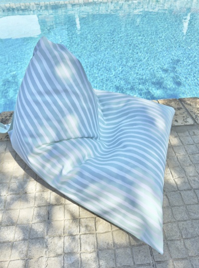 Poltrona puff exterior riscas brancas e azul junto a piscina