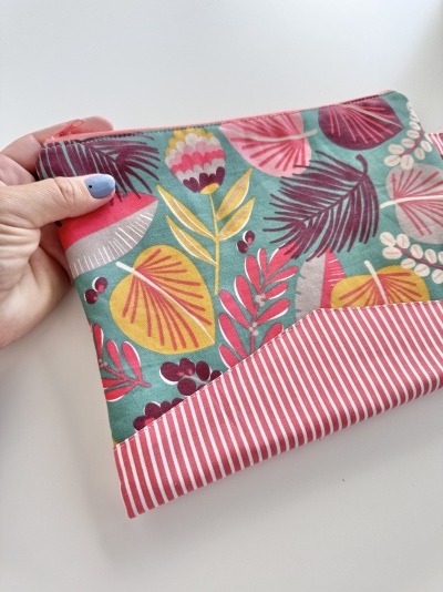 Necessaire de tecido com padrão floral colorido e riscas vermelhas