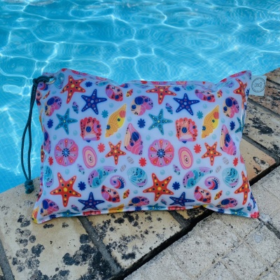 Almofada com padrão de estrelas-do-mar e conchas junto à piscina