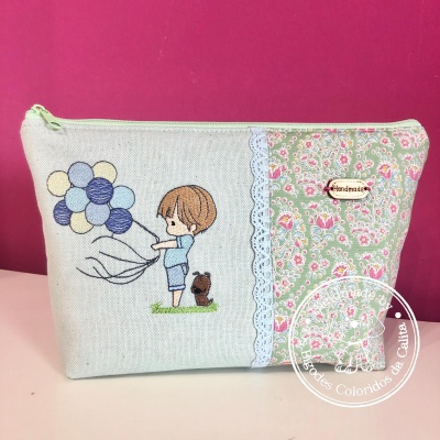 Necessaire de tecido com menino e urso segurando balões e padrão floral com renda