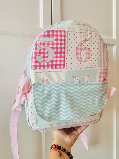 Mochila pequena colorida com números, bolso frontal azul claro com padrão de ondas