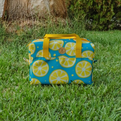Bolsa azul com padrão de limões amarelos sobre relva verde ao ar livre