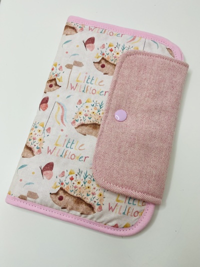 Estojo tecido com padrão ouriços, borboletas e texto Little Wildflower, bordas rosa e aba rosa claro com botão lilás