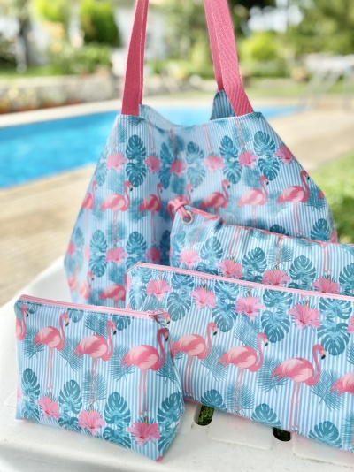 Bolsas de tecido azul claro com padrão de flamingos cor-de-rosa e folhas verdes junto a piscina