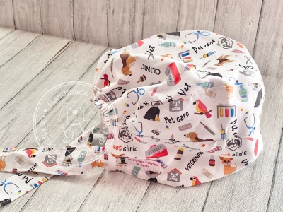 Gorro cirúrgico branco com padrão veterinário colorido em superfície de madeira clara