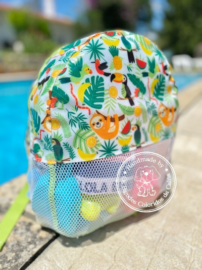 Mochila infantil colorida com padrão de animais tropicais e bolso de malha, junto a piscina ao ar livre