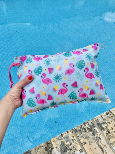 Bolsa azul claro com padrão de flamingos e frutas junto à piscina