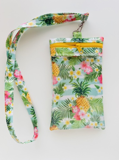 Bolsa pequena com padrão tropical e fecho amarelo, com alça para o pescoço.