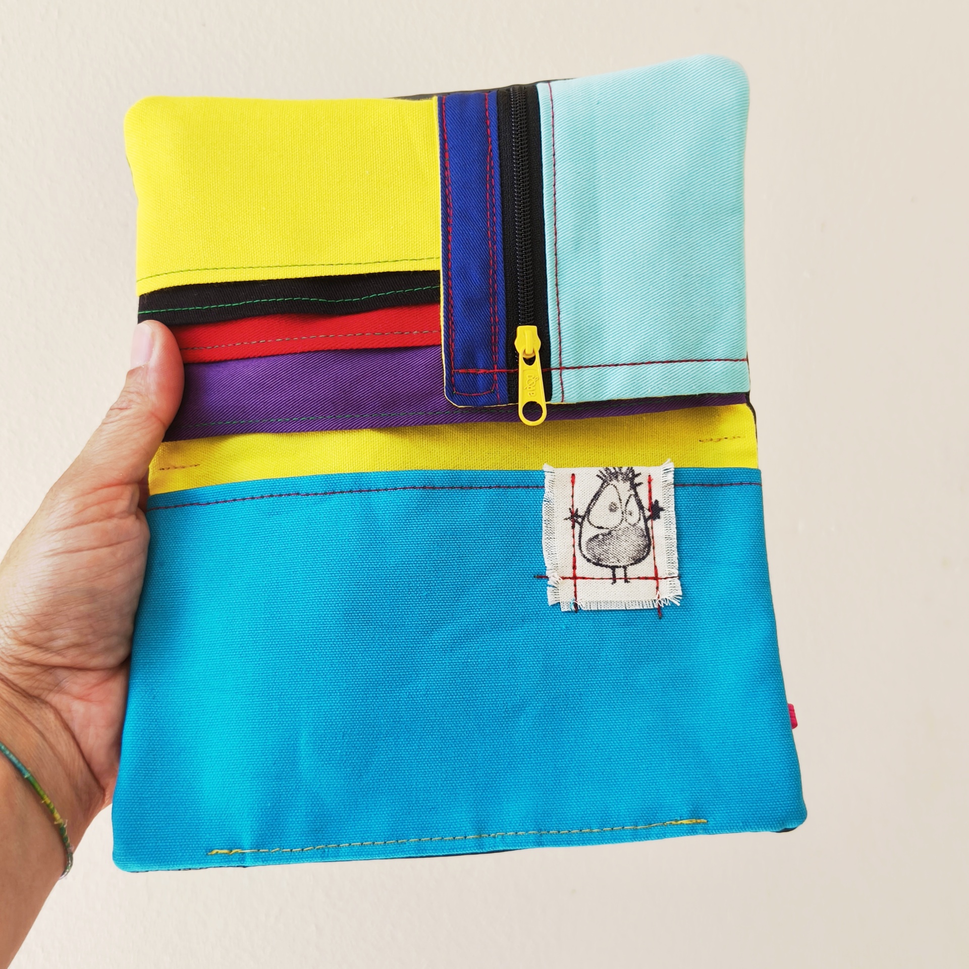 Carteiras porta-tudo! Bolsa colorida em tecido com fecho de correr e etiqueta com desenho de pássaro