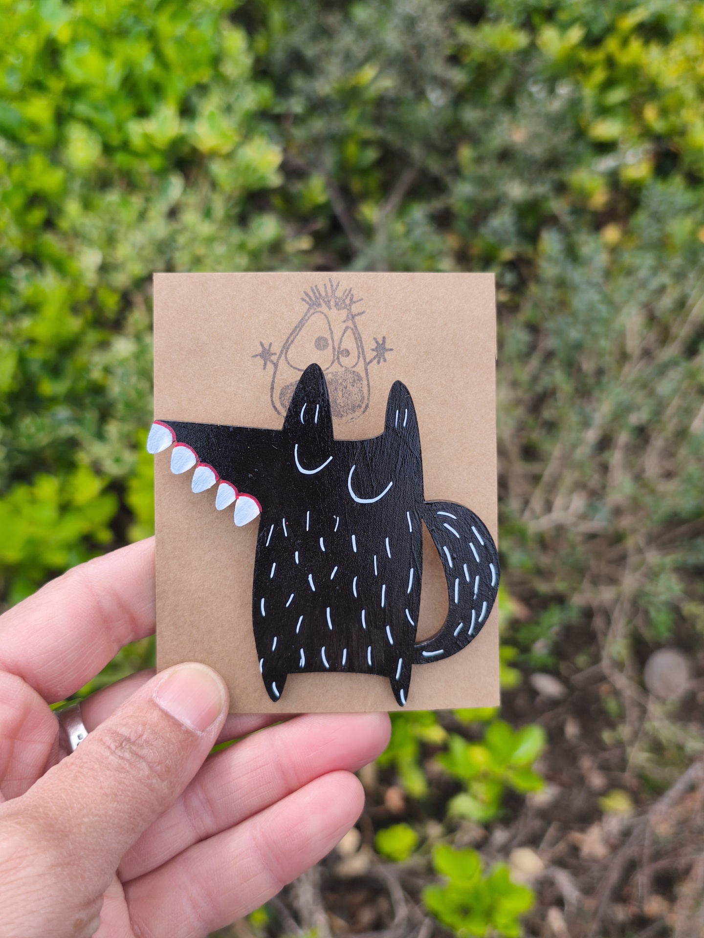 Alfinete lobo! Broche em madeira preto com dentes brancos e detalhes vermelhos num cartão castanho com desenho a lápis