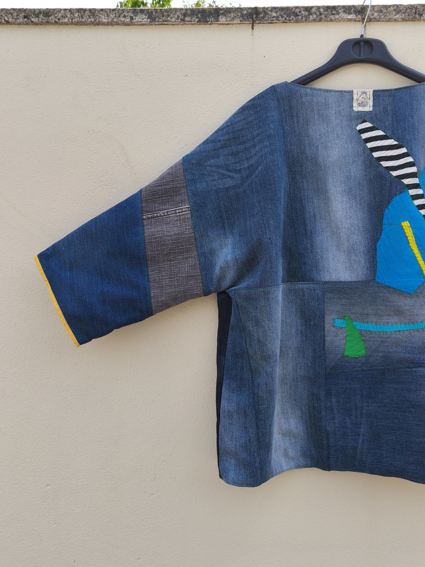 Casaco de ganga Trapo #4 Blusão patchwork azul e cinzento com aplicação colorida pendurado num cabide