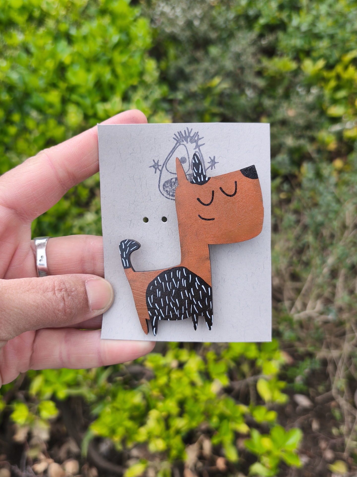 Alfinete cão #2! Broche de madeira pintado como cão estilizado cor de caramelo com manchas pretas e detalhes brancos em cartão cinzento