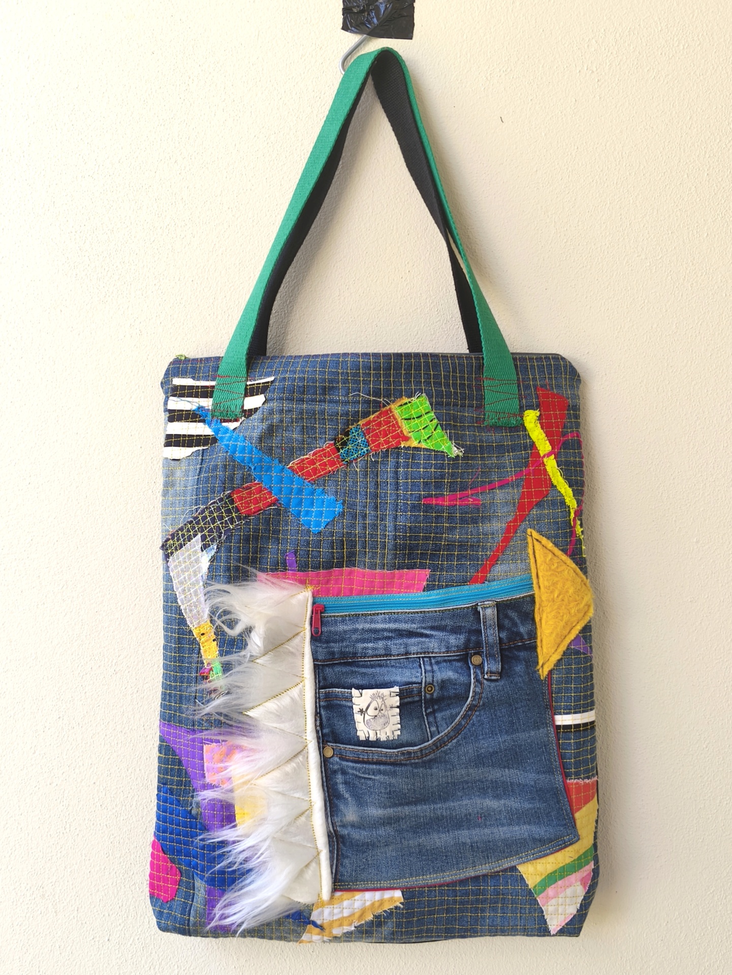 Bolsa/Mochila Mala de tecido azul com bolso jeans, alças verdes e detalhes coloridos