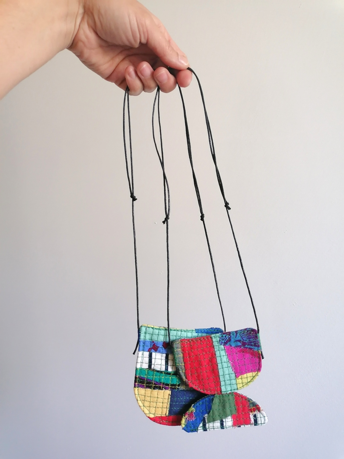 Colar Trapo Três pequenas bolsas coloridas penduradas em cordão fino preto