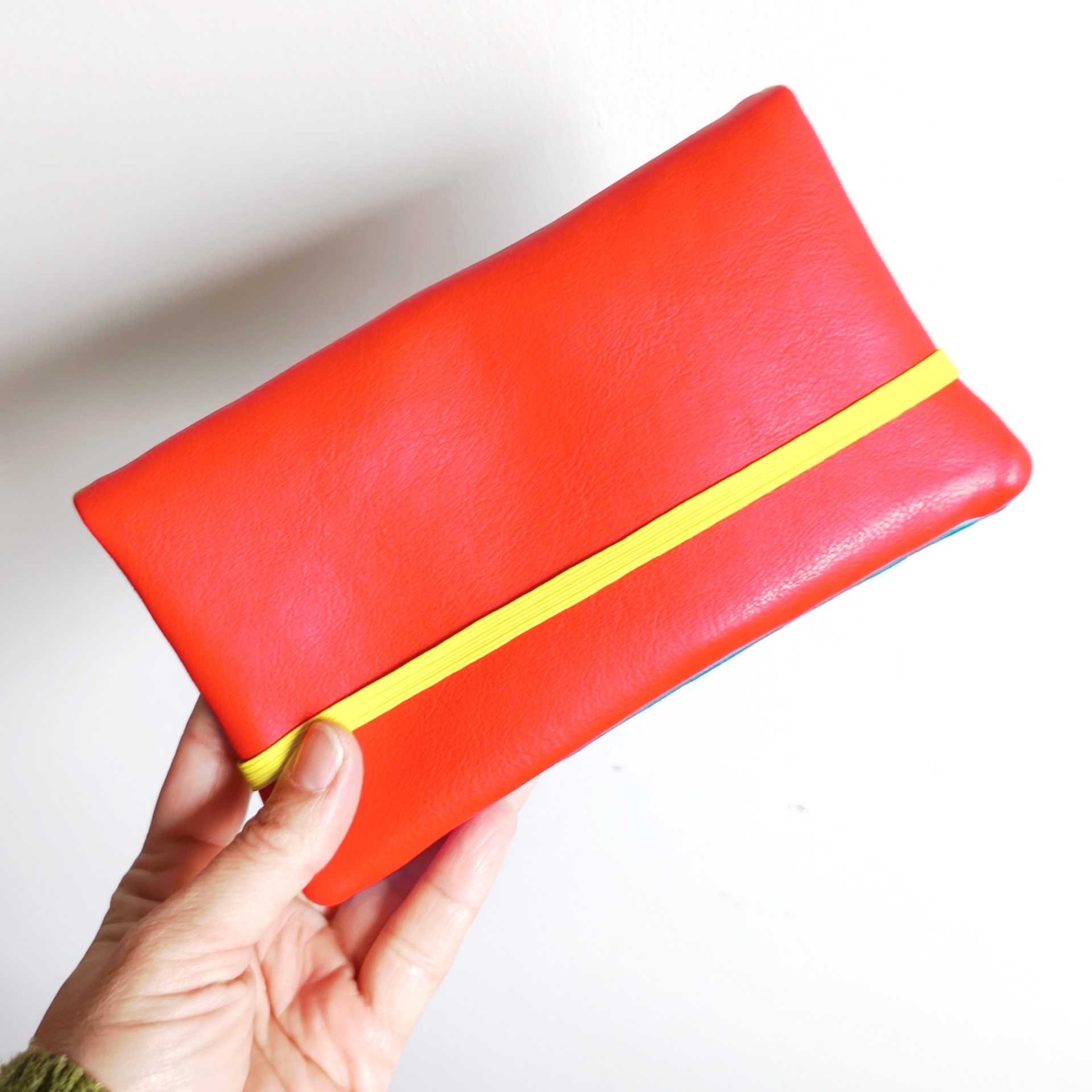 Carteiras porta-tudo! Carteira vermelha com elástico amarelo segurada por mão