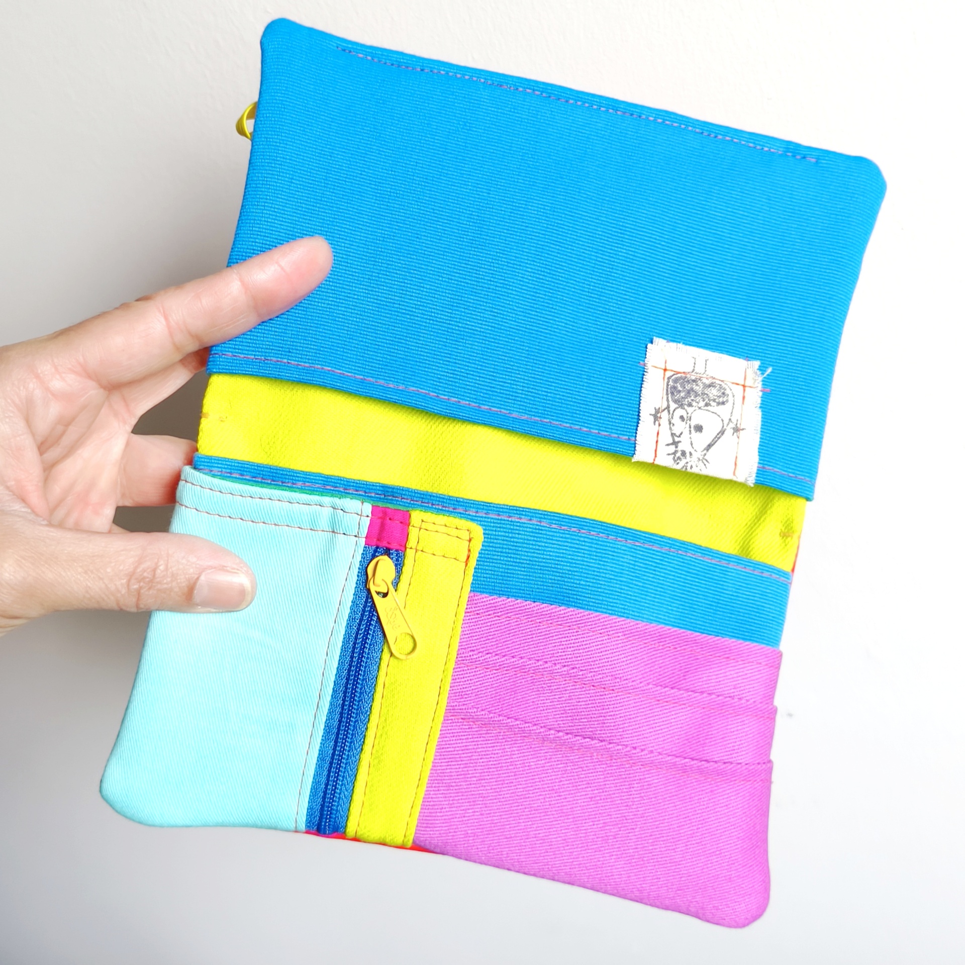 Carteiras porta-tudo! Carteira colorida com fecho zip amarelo às riscas azuis, rosa, amarelo e azul claro.