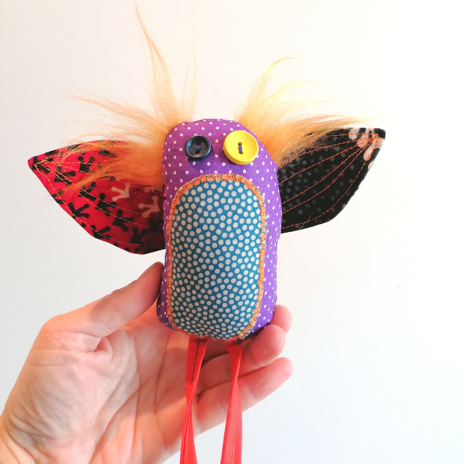 Passatortos! Brinquedo artesanal em forma de pássaro em vários tecidos coloridos segurado por uma mão