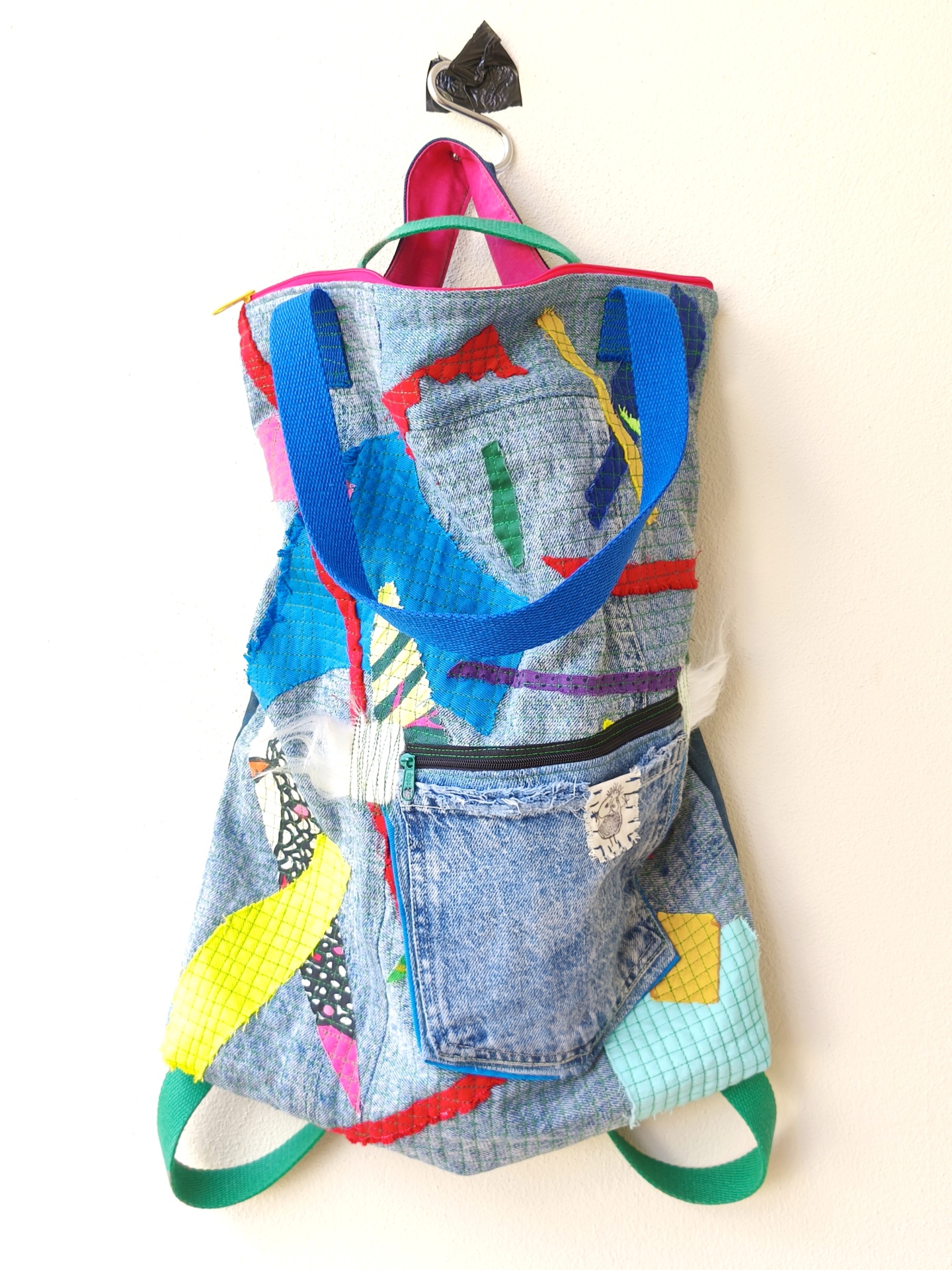 Bolsa/Mochila Mochila colorida de tecido com padrão texturizado e bolso de jeans pendurada.