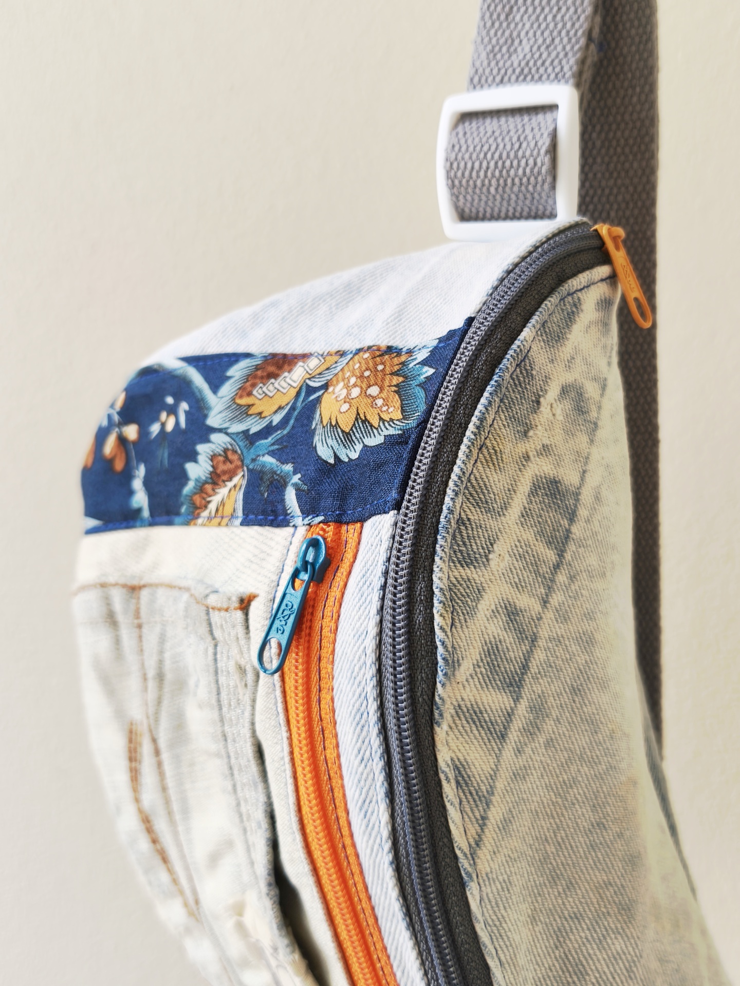 Bolsa de cintura Os básicos! Mala de tecido padrão jeans claro com fechos de correr laranja e azul, padrão floral azul na parte superior e tira cinzenta