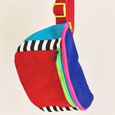 Mochila colorida em tecido com vários fechos e bolso às riscas