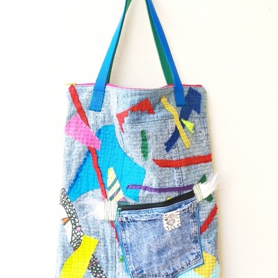 Mala de tecido cinza com padrões coloridos abstratos e bolso de ganga