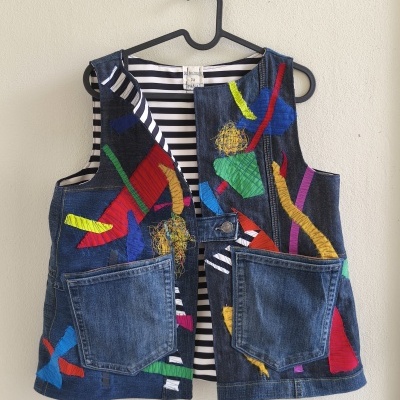 Colete de ganga com estampas coloridas e interior listrado pendurado num cabide