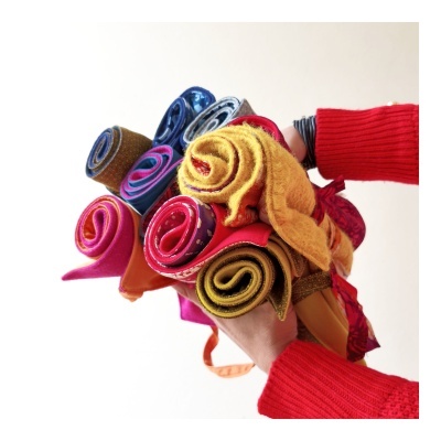 Tecido enrolado colorido segurado por mãos com mangas vermelhas