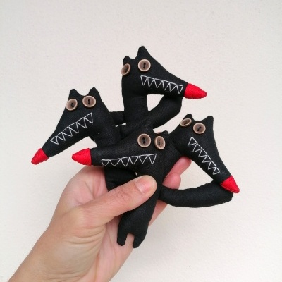 Três bonecos de lobo de tecido preto com olhos castanhos e focinho vermelho