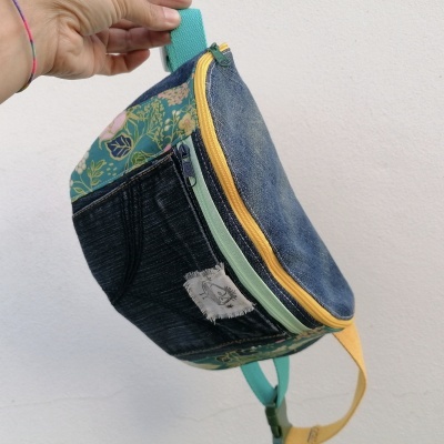 Mochila pequena de tecido com ganga azul, padrão floral e zíper amarelo