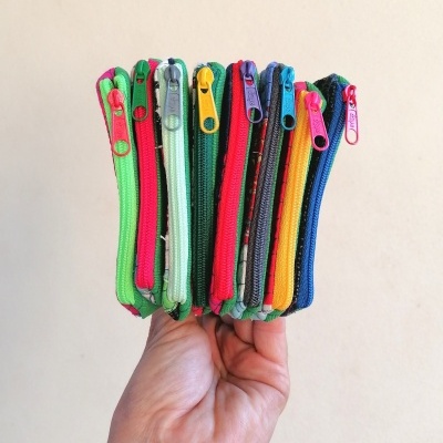 Carteiras pequenas coloridas com fechos de correr em mão sobre fundo bege