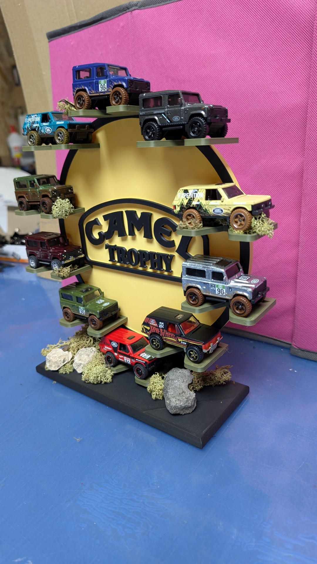Miniaturas de carros todo-o-terreno coloridos expostas em suporte preto e amarelo com texto GAME TROPHY