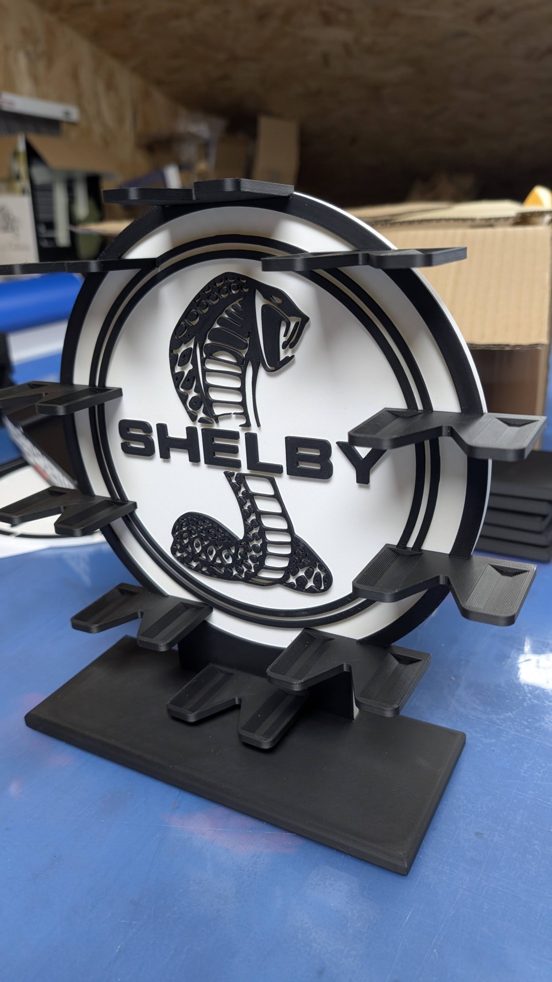Suporte de exposição negro e branco com logótipo Shelby e padrão de cobra