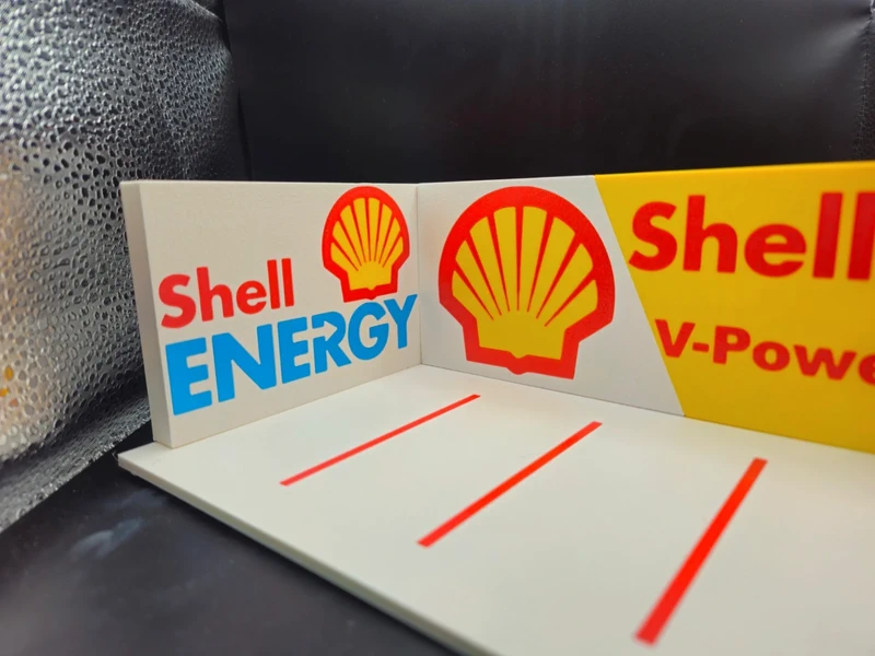 Display promocional Shell ENERGY com logótipos em vermelho, amarelo e azul, linhas vermelhas sobre fundo branco e amarelo