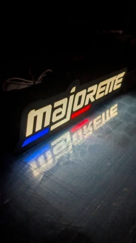 Luz decorativa majorete branca com sublinhados azul e vermelho, refletida em superfície escura