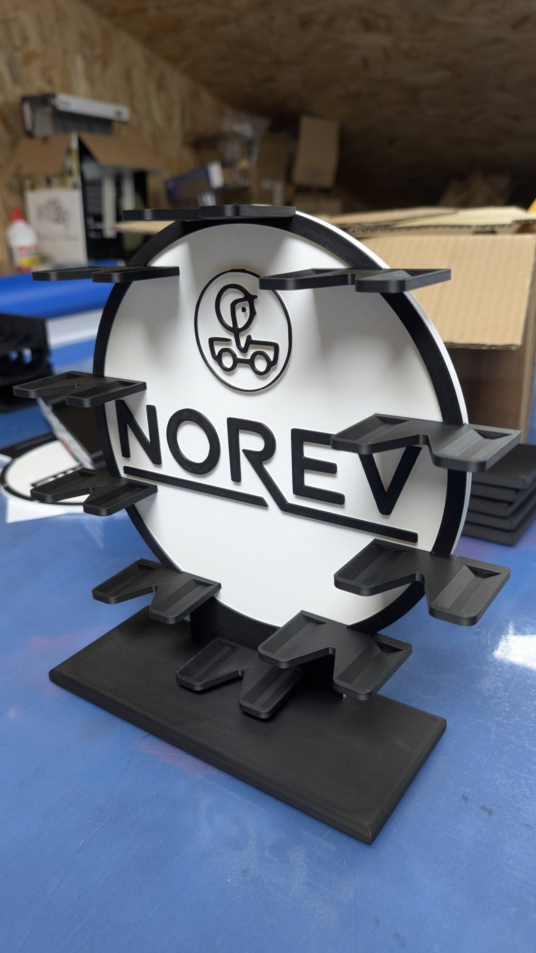 Suporte expositor preto e branco com o texto NOREV e prateleiras para miniaturas