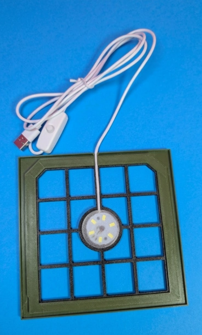 Base quadrada verde com grelha e luz LED central ligada a cabo USB branco