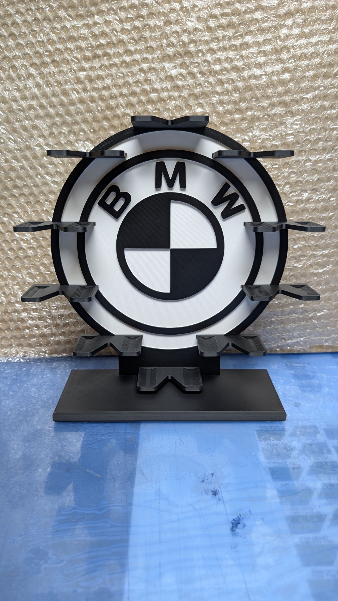 Suporte preto circular com logótipo BMW preto e branco