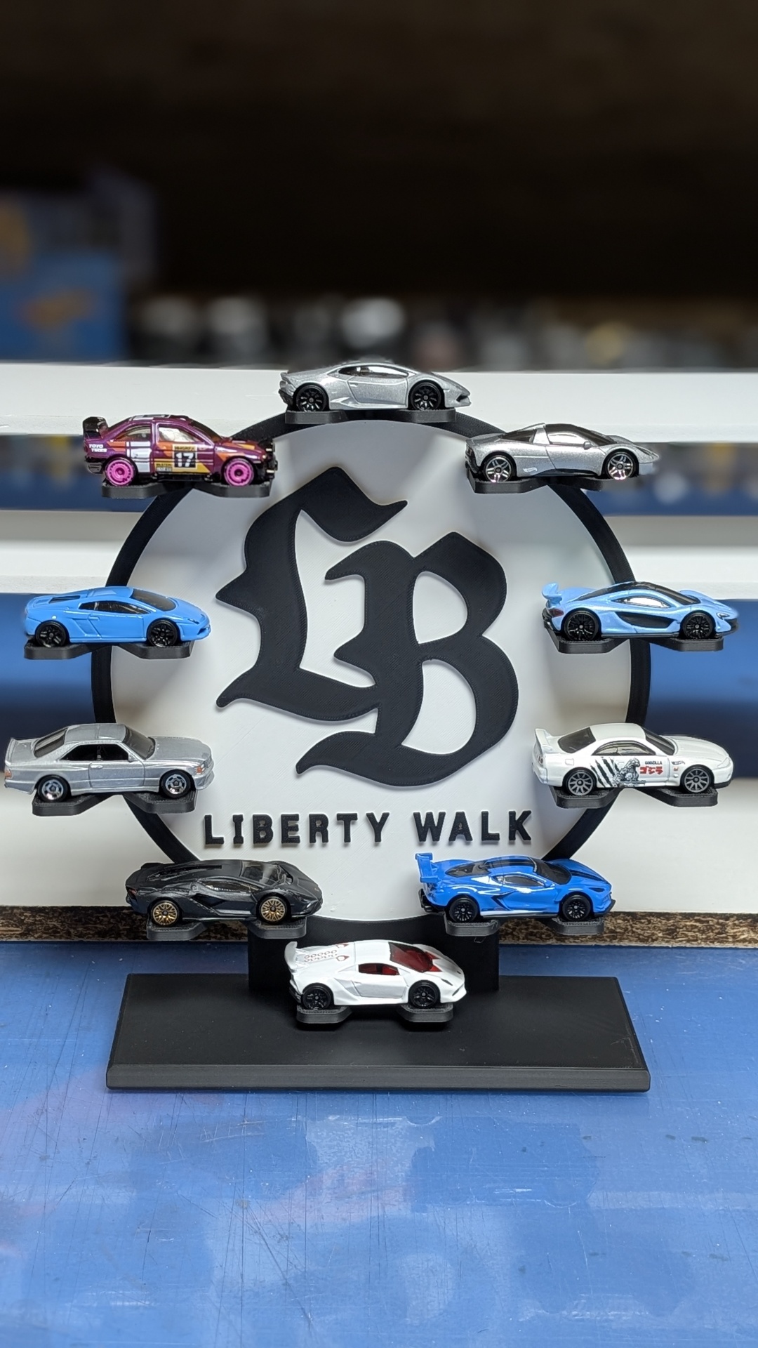 Miniaturas de carros exibidas num suporte com logo Liberty Walk