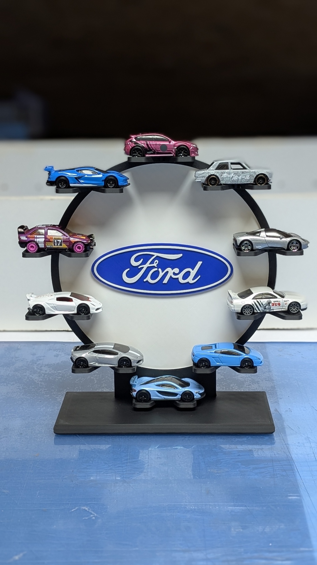 Conjunto de miniaturas de carros coloridos em suporte circular com logótipo Ford ao centro.