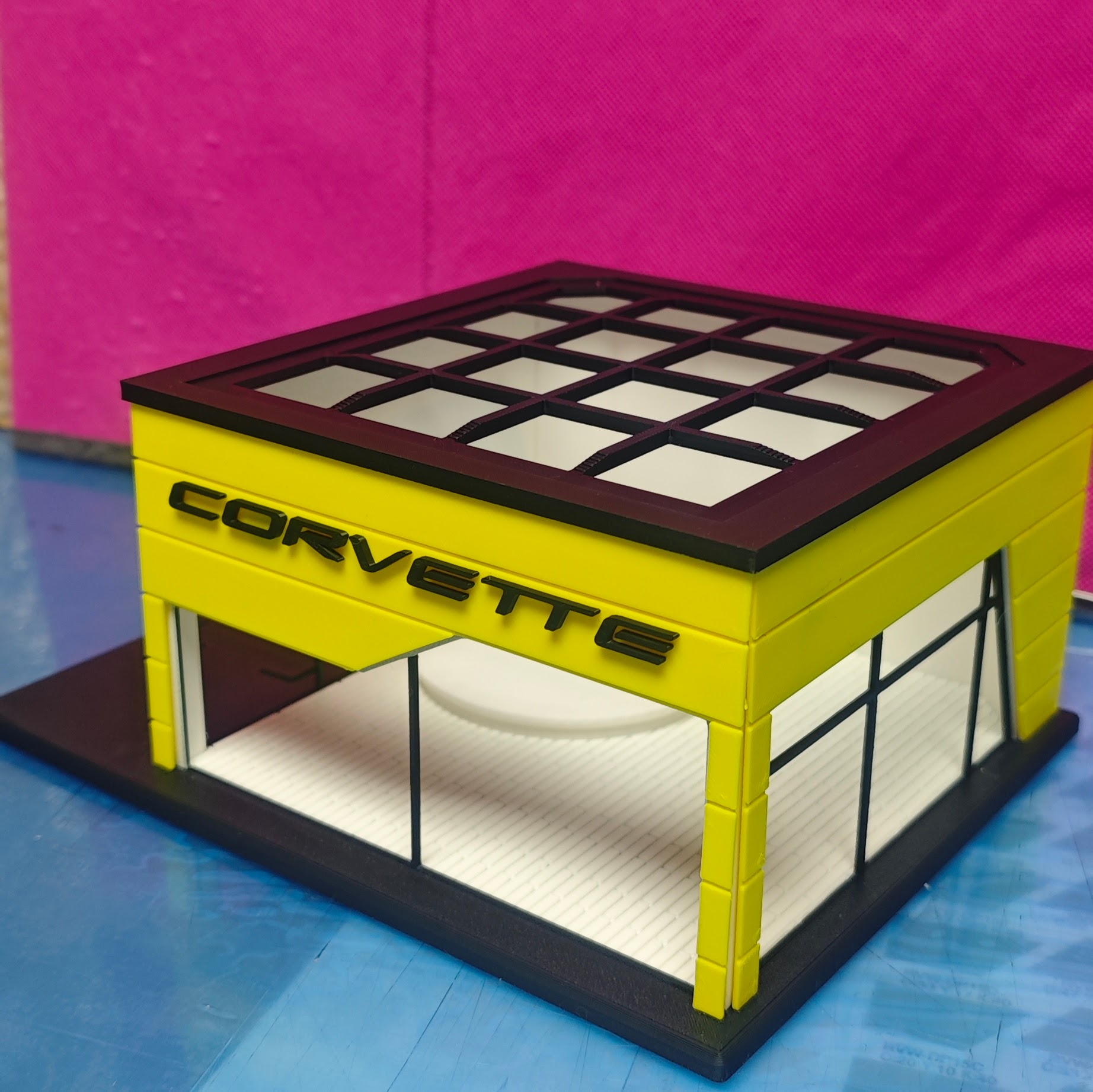 Miniatura de garagem amarela com janelas de vidro e letras CORVETTE pretas