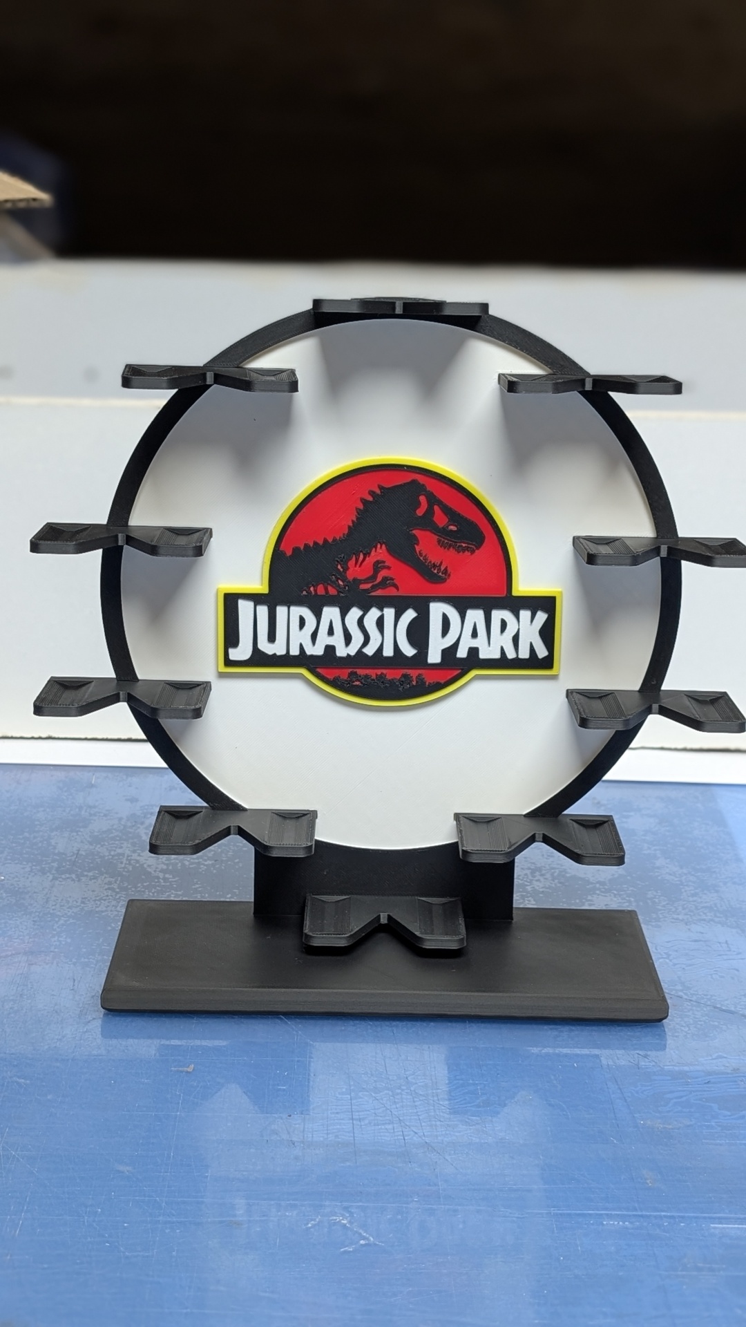 Suporte preto redondo para óculos com logo Jurassic Park