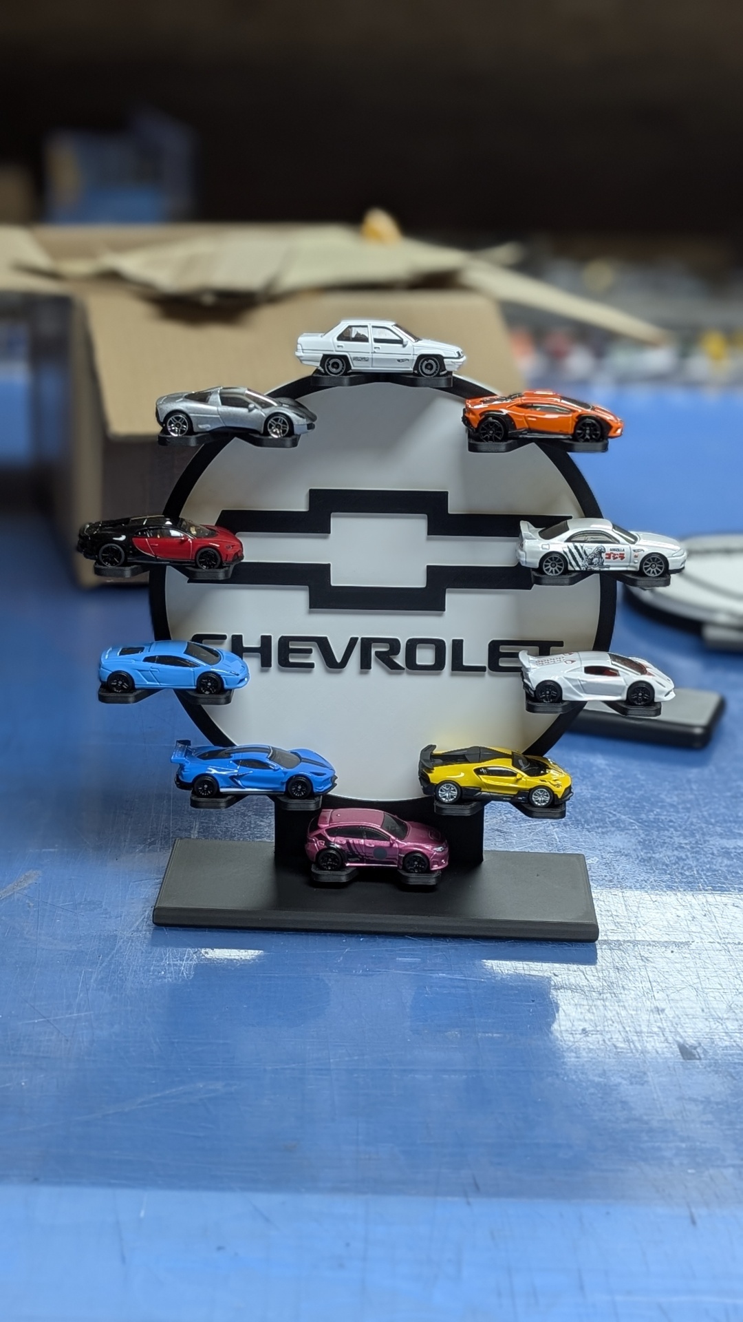 Expositor preto com placa branca CHEVROLET e miniaturas de carros coloridos