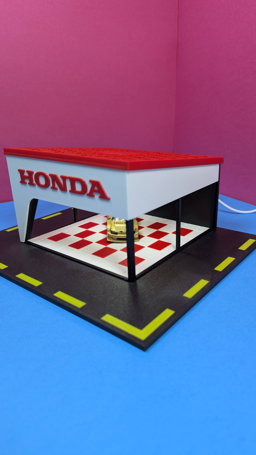 Miniatura de garagem Honda com carro dourado e chão de azulejos vermelhos e brancos