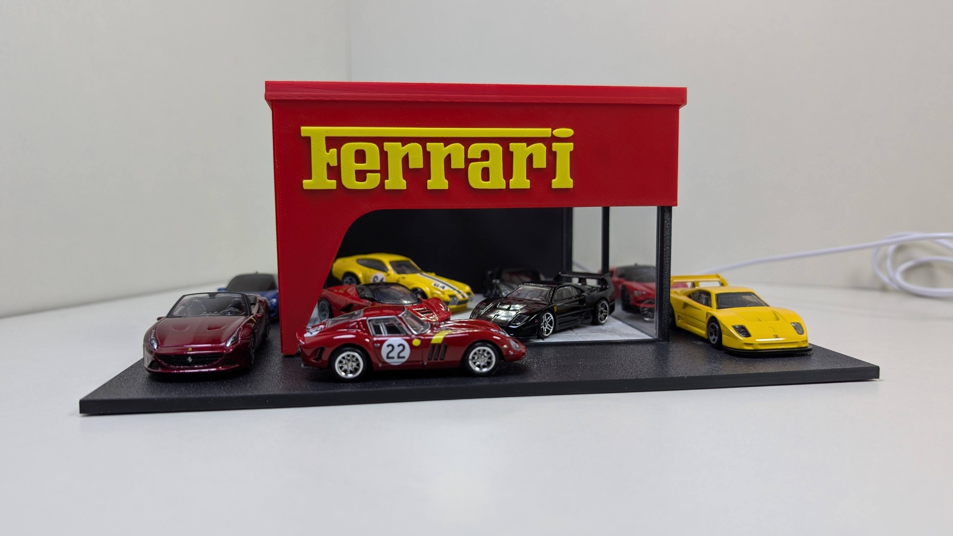 Miniaturas de carros Ferrari em exposição com suporte vermelho e texto amarelo Ferrari