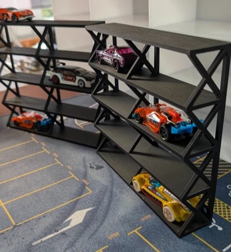 Estante preta com miniaturas de carrinhos de corrida coloridos em prateleiras inclinadas, tapete com desenhos de estrada e estacionamento.