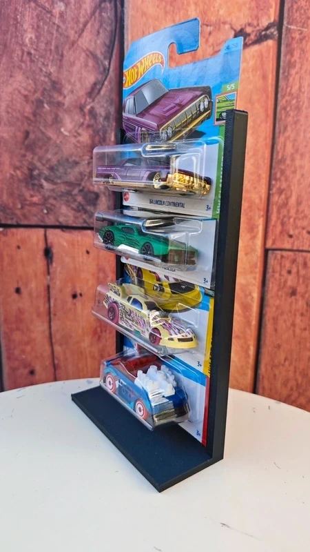 Conjunto de quatro carros Hot Wheels em embalagens, expostos em suporte preto