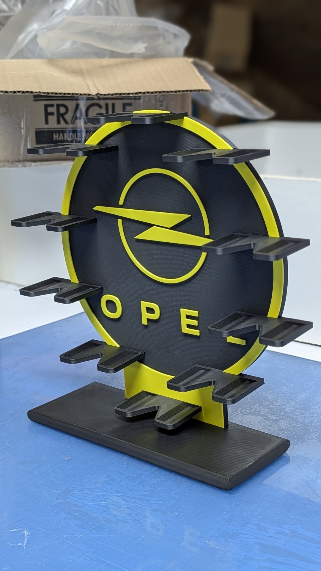 Suporte preto e amarelo com logótipo Opel e várias pequenas prateleiras.