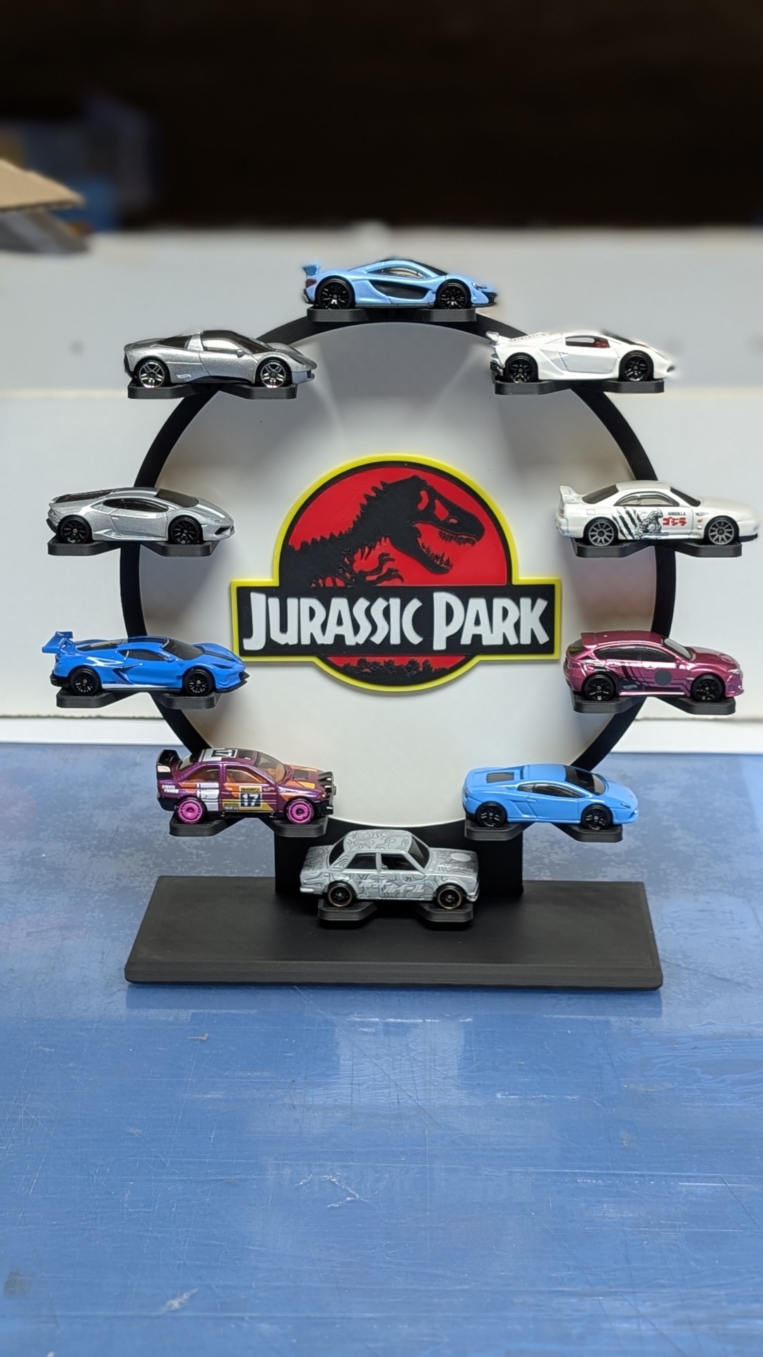 Expositor circular com miniaturas de carros e logótipo Jurassic Park no centro