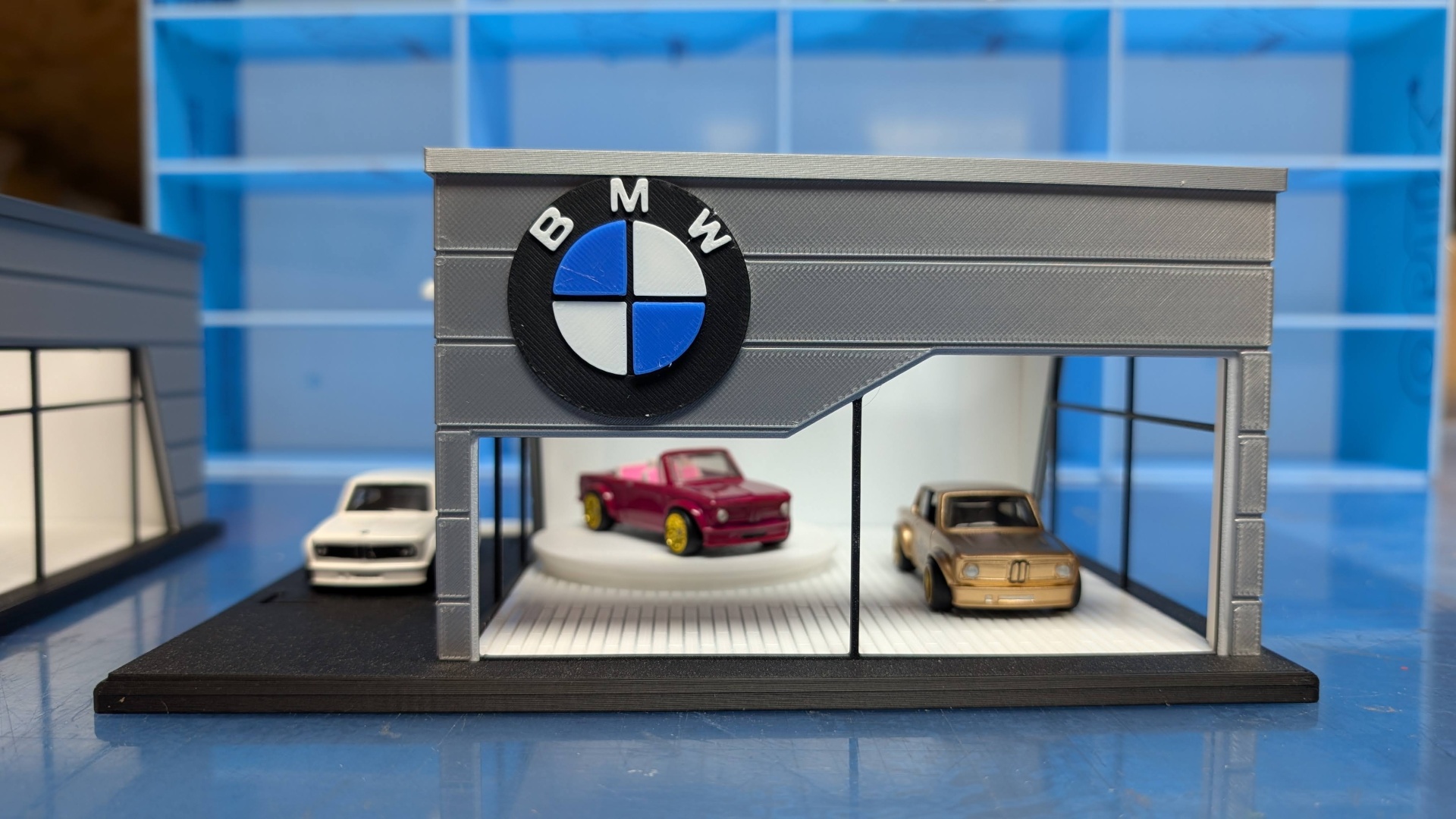 Miniatura de concessionário BMW com três carros em miniatura.